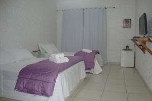 巴乌鲁Black Hotel的一间卧室配有两张床、紫色床单和毛巾
