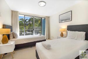 黄金海岸阿苏拉绿色度假酒店的一间卧室设有两张床和大窗户
