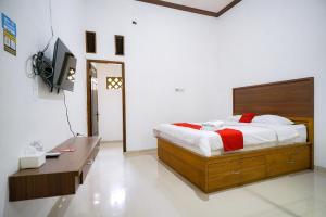 LampungRedDoorz at Jalan Basuki Rahmat Lampung的一间卧室配有一张床、一张书桌和一台电视。