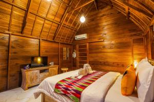 珀尼达岛The Tukad Gepuh Cottage and Resto的一间带木墙的卧室、一张床和电视