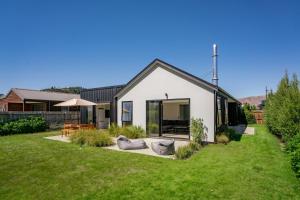 瓦纳卡Northlake Hideaway - Wanaka Holiday Home的绿色庭院的白色房子