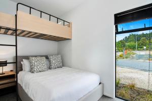 凯特里特里Kotuku Apartment - Kaiteriteri Holiday Unit的一间卧室设有一张双层床和大窗户。