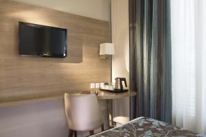 巴黎杜尔那马莱酒店的酒店客房设有一张桌子和一台墙上的电视