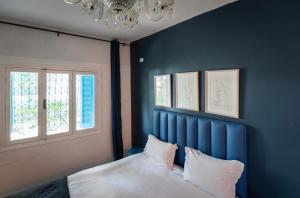 西迪·布·赛义德La Villa Des Oliviers的一间卧室设有蓝色的墙壁和一张带枕头的床。
