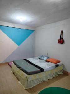 伊洛伊洛Guest Homey的墙上有吉他的房间的一张床位