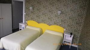 索恩河畔沙隆圣让酒店的一间卧室设有两张床和黄色床头板