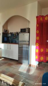 马赛Petit cocon à Mourepiane的厨房配有冰箱和红色窗帘