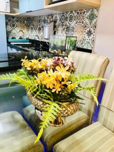 萨尔瓦多apart hotel 2 quartos frente mar的摆满黄色花朵的花瓶,坐在椅子上