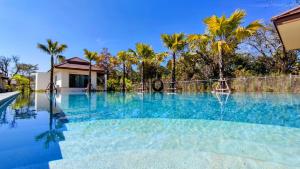 乌隆他尼Isan Golf & Adventure Hotel的一座拥有蓝色海水和棕榈树的游泳池