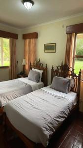 奈瓦沙Kwezi Cottage at The Great Rift Valley Lodge & Golf Resort Naivasha的卧室设有两张床,带两个窗户