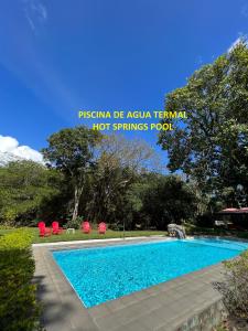埃尔巴列德安通La Casa de los Patos的一个带2把红色椅子的游泳池和一个游泳池