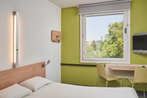 弗罗茨瓦夫ibis budget Wrocław Południe的一间卧室配有一张床、一张书桌和一个窗户。