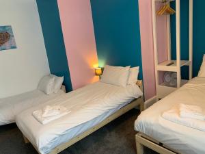 伯翰姆昂斯The Royal Clarence Hotel (on the Seafront)的两间双床间,拥有蓝色和粉红色的墙壁