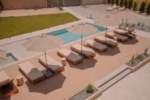 卡特罗斯Marble Luxury Suites的享有带椅子和遮阳伞的游泳池的上方景致