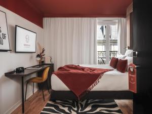 巴黎赛文酒店的一间卧室配有一张床、一张书桌和一个窗户。