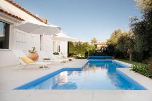 Plaia GrandeVilla LAVINIA MARE E PISCINA PRIVATA的一个带白色椅子和遮阳伞的游泳池