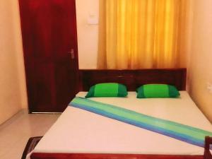蒂瑟默哈拉默New Green Garden Hotel & Safari的一间卧室配有一张带绿色枕头的床