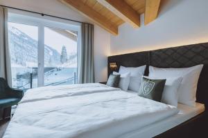 萨尔巴赫GLEMM by AvenidA Superior Hotel & Residences的卧室设有一张大白色的床和大窗户