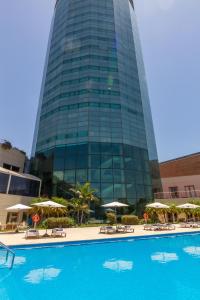 科尔多瓦Quinto Centenario Hotel的一座高大的建筑,在一座建筑前设有一个游泳池