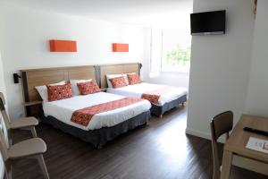 圣艾蒂安德拜戈里玛尼可热尼雅旅馆的一间卧室配有两张床和一张桌子及椅子