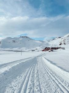 贝特斯托尔Bygdin Høyfjellshotell的一条有雪覆盖的道路,远处有一座房子