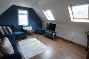 贝尔法斯特Belfast Loft的客厅设有蓝色的沙发和2扇窗户。
