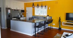德班Rose Holiday Home的厨房设有黄色的墙壁和带酒吧凳的台面