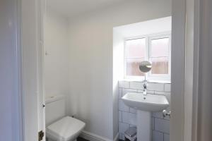 惠特比Stable Cottage的白色的浴室设有卫生间和水槽。