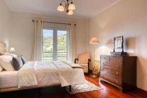 蓬他达维托亚Lidia's Place, a Home in Madeira的一间卧室配有一张床、一个梳妆台和一扇窗户。