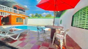 里考尔特LA MANUELA- VILLA CON PISCINA PRIVADA的庭院配有桌椅和红色遮阳伞。
