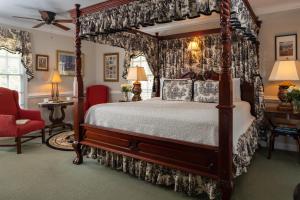 威廉斯堡威廉斯堡白宫酒店 的一间卧室配有天蓬床和红色椅子