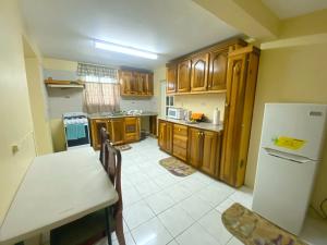 金斯敦Russell Heights Vacation Home的厨房配有木制橱柜、桌子和冰箱。
