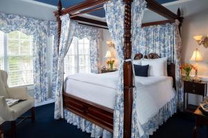 威廉斯堡威廉斯堡白宫酒店 的一间卧室配有一张带蓝色窗帘的天蓬床