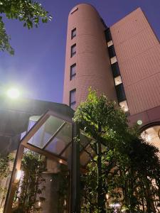 犬山市Inuyama City Hotel的前面有一棵树的高大的砖砌建筑