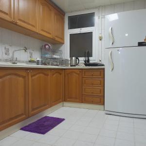 阿布扎比A Home Away From Home的厨房配有木制橱柜和冰箱。
