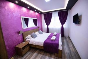 萨拉热窝Villa Panorama的一间紫色卧室,配有一张床和一台电视
