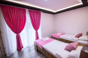 萨拉热窝Villa Panorama的客房设有两张床和一个带红色窗帘的窗户。
