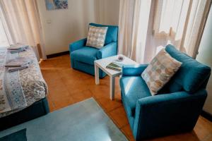 El FigaróCasa les Pomeretes的客厅配有2把蓝色椅子和桌子