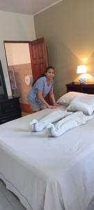 圣何塞特里亚农宾馆的一位站在床上的女士,上面有毛巾