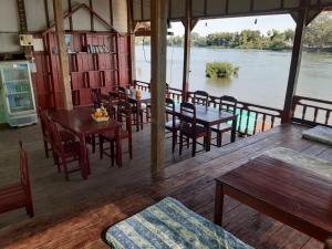 东德岛Mr. Phaos Riverview Guesthouse & Restaurant的一间带桌椅并享有河景的餐厅