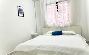 实达阿南Melur Homestay的白色卧室配有一张带蓝色枕头的床