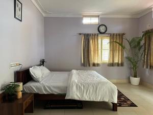 班加罗尔Rustic Village Farmhouse的卧室配有一张床,墙上挂着一个钟