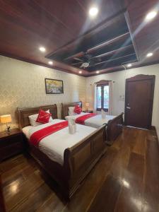 琅勃拉邦Luang Prabang Villa Sirikili River View的一间大卧室,配有两张带红色枕头的床