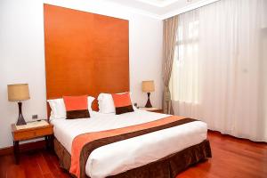 Meru梅鲁阿尔巴酒店的酒店客房配有一张带橙色枕头的大床