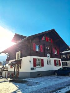 因特拉肯Adventure Guesthouse Interlaken的大型木制房屋,设有红色百叶窗