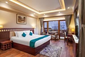 列城Ashoka Ladakh的酒店客房设有一张床、一张书桌和一个阳台。