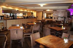 贝灵厄姆Wingate by Wyndham Bellingham Heritage Inn的一间带木桌椅的餐厅和一间酒吧