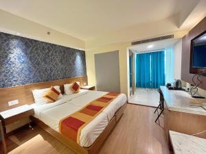 新德里The Orion Plaza - Nehru Place的酒店客房,配有床和电视
