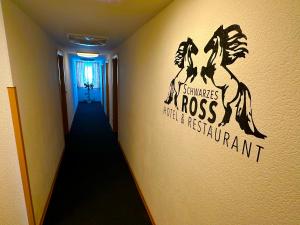 奥泊维森塔尔Schwarzes Ross Hotel & Restaurant Oberwiesenthal的墙上有标志的走廊