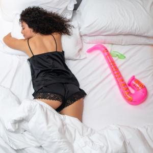 莱切Arryvo Hotel的躺在床上的女人,床上有粉红色的火烈鸟玩具